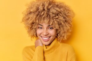 Femme afro souriante avec des cheveux bouclés blonds