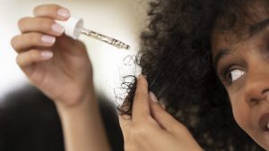 Femme noire utilisant un produit Morija care dans ses cheveux afros