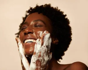 Femme afro qui se lave le visage en souriant