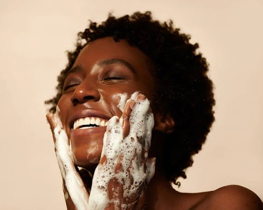 Femme afro qui se lave le visage en souriant